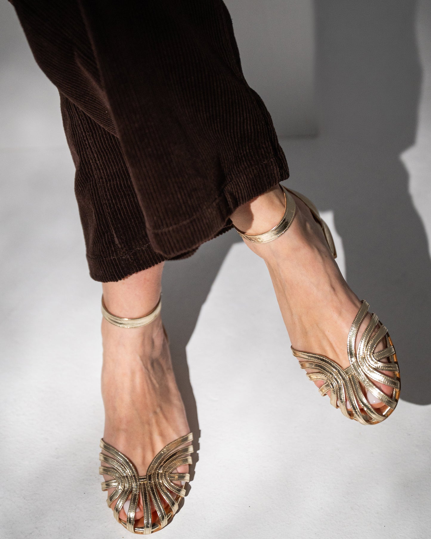 Gold wedding shoes worn by a person on a light background