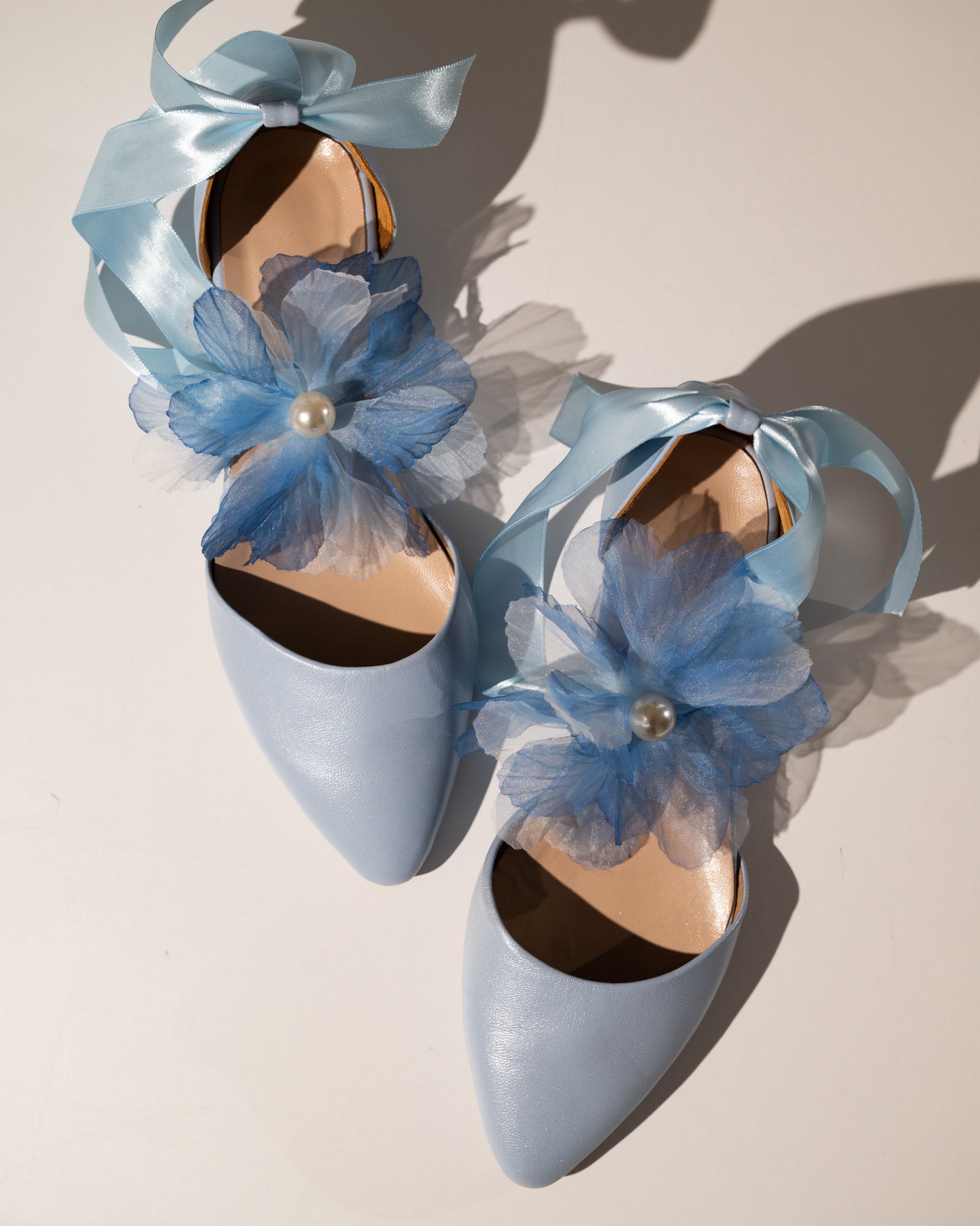 Light blue shoes with floral decorations on a neutral background