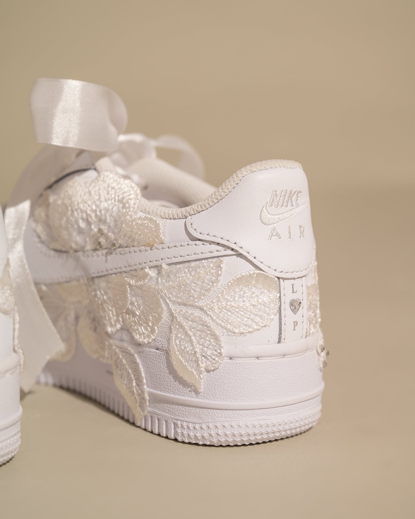 White sneaker with floral lace design on a beige background