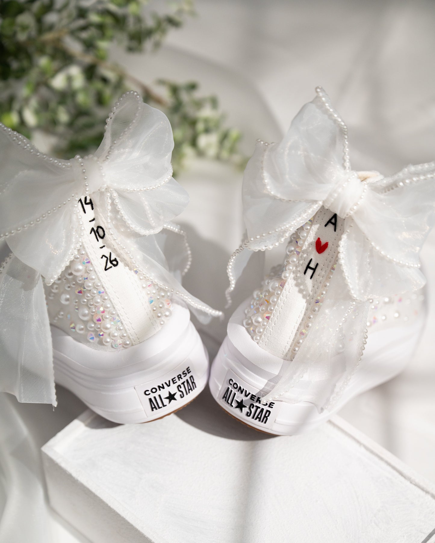 White Converse All Star shoes with decorative elements on a white surface.