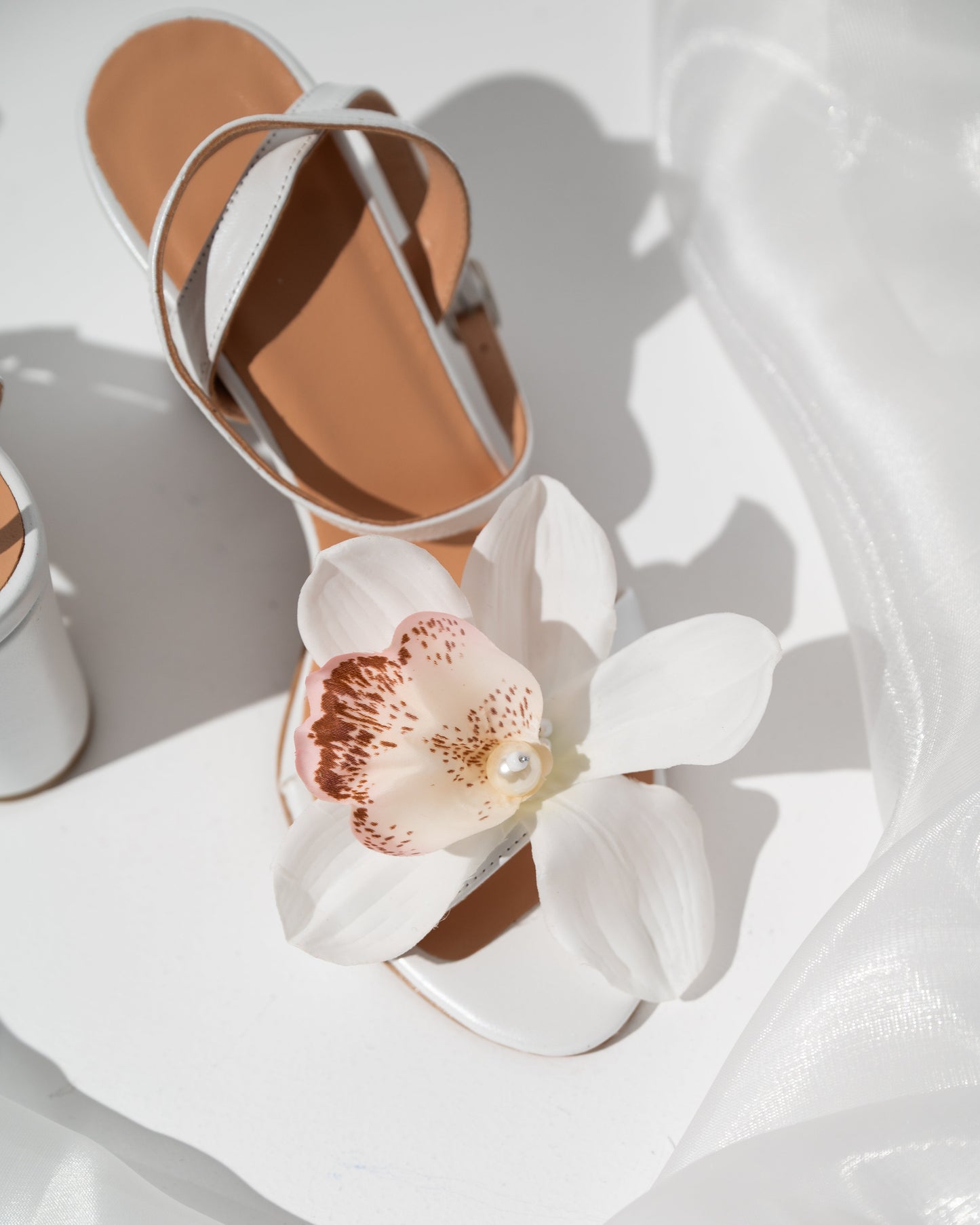 Sandal with a large white flower decoration on a white background