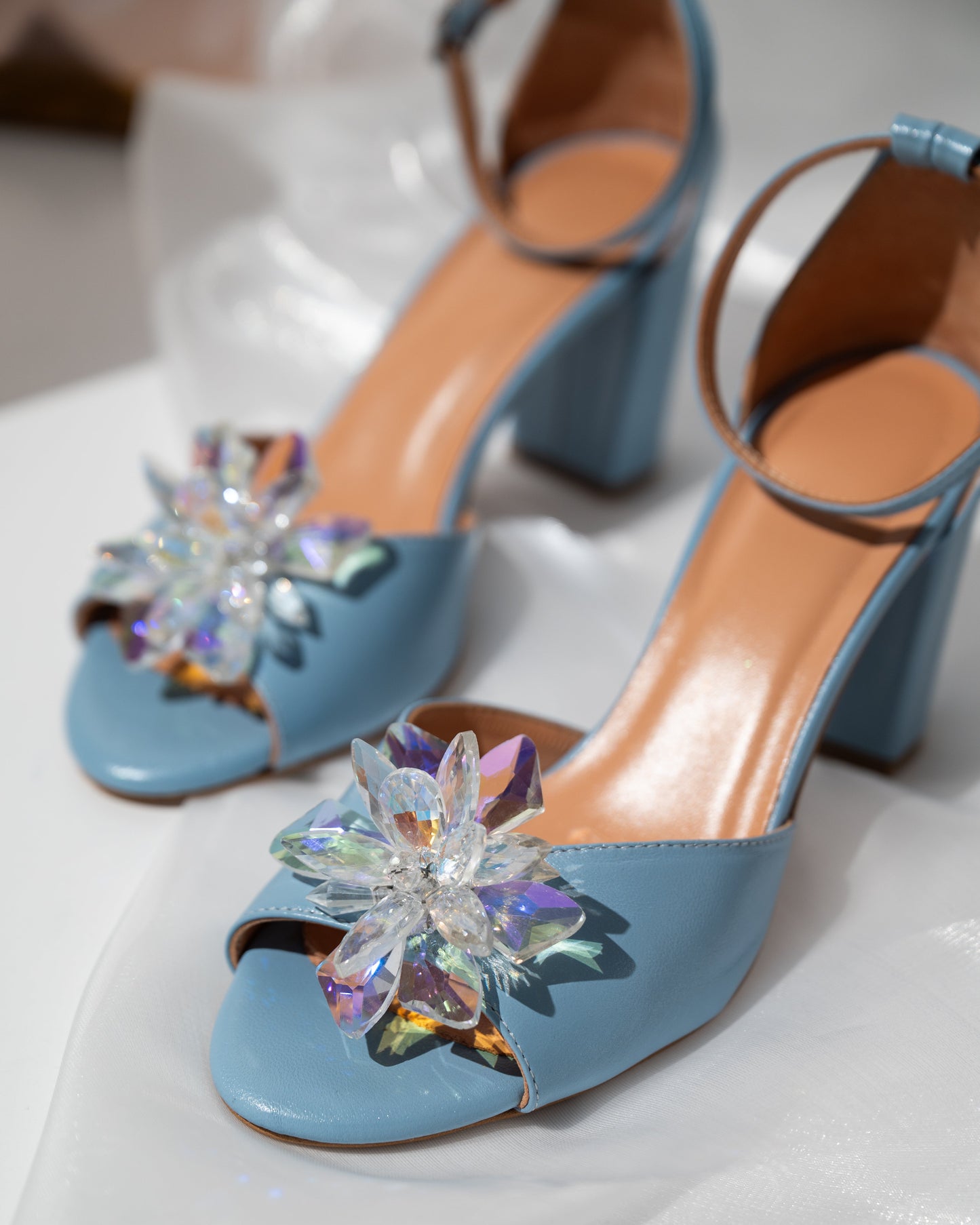 Blue high-heeled shoes with decorative flowers on a white surface