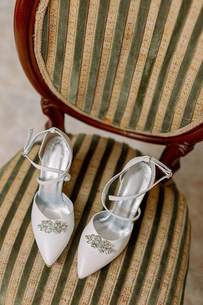 White high-heeled shoes with embellishments on a striped chair