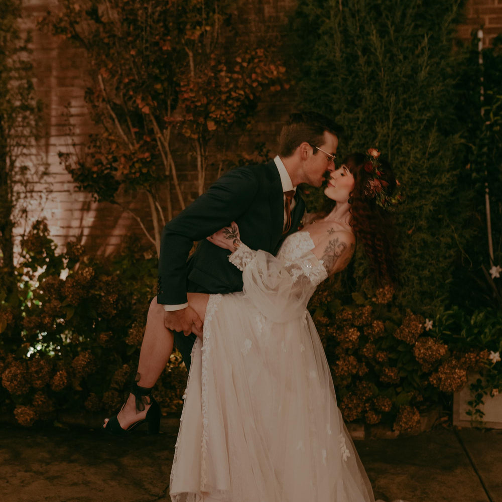 Couple sharing a kiss in a romantic setting with floral decorations.