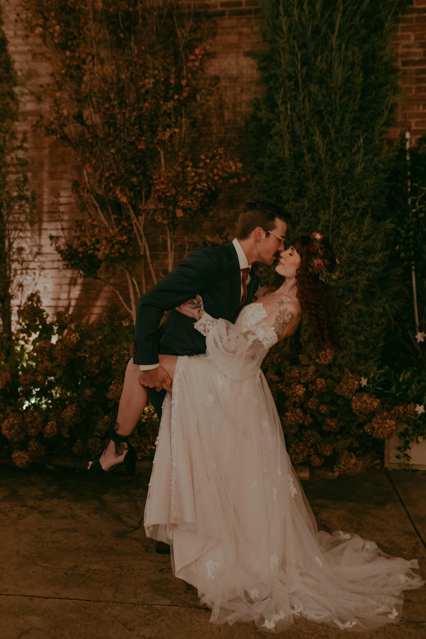 Couple sharing a kiss in a romantic setting with floral decorations.