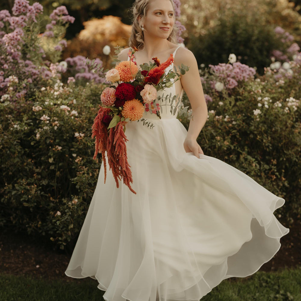Woman in a white dress holding a bouquet of flowers in a garden setting