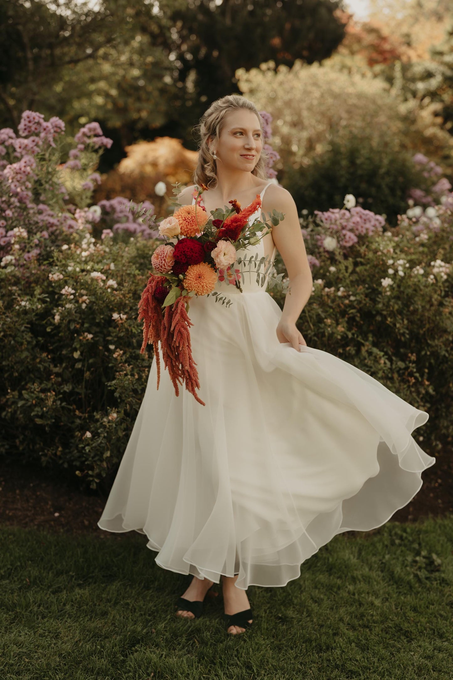 Woman in a white dress holding a bouquet of flowers in a garden setting