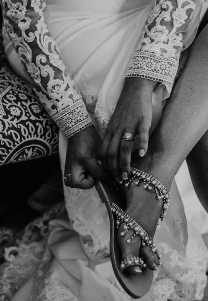 Person wearing a sandal with intricate beading, close-up shot.