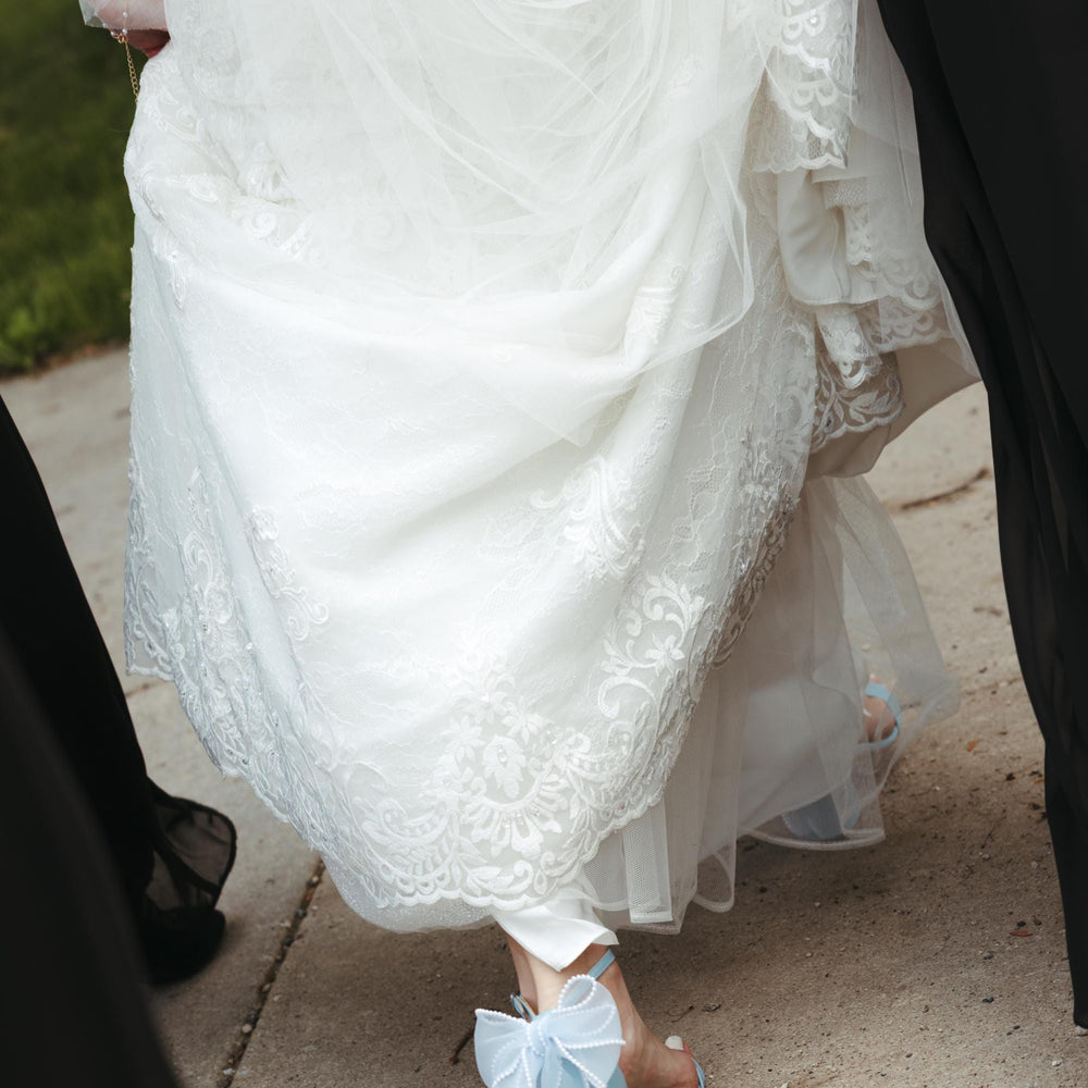 White lace dress with blue bow sandals on a sidewalk