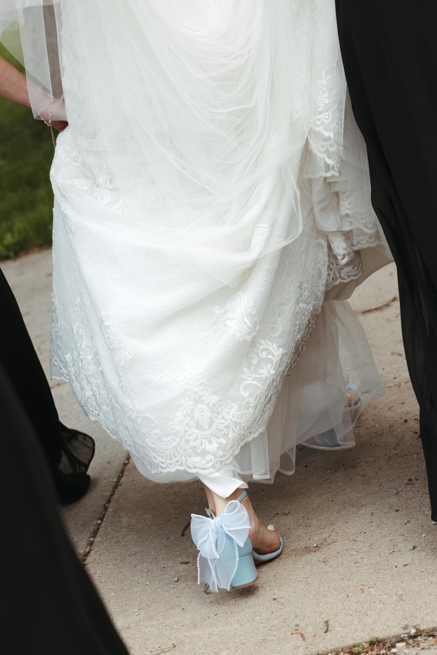White lace dress with blue bow sandals on a sidewalk